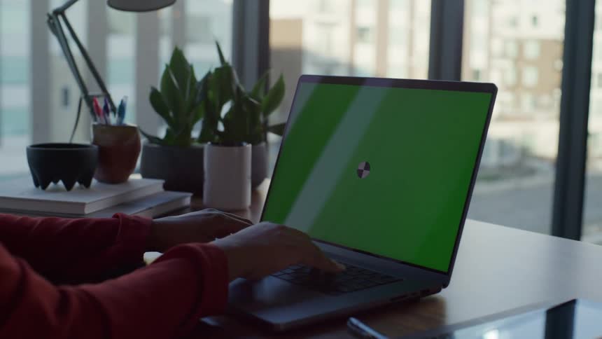 A woman sitting at her desk typing on a laptop