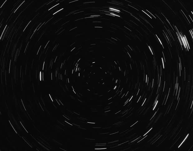 In a changing scene a point stretches from an orb in the darkness and a whirlpool spins and orbs rise in front of white vertical lines and it all turns white