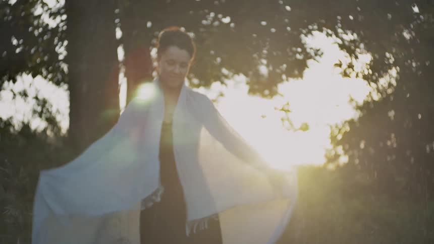 A woman snaps her shawl to unfold it before placing it around her shoulders