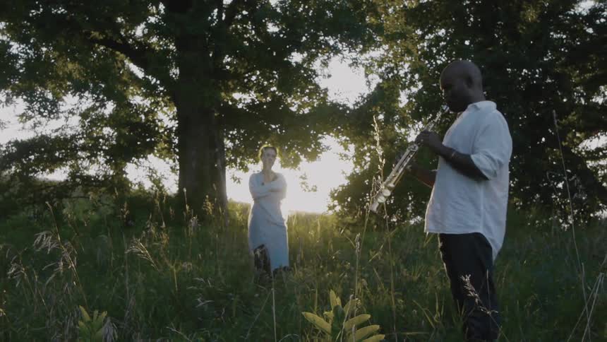 Man playing an instrument as a woman watches at sunset