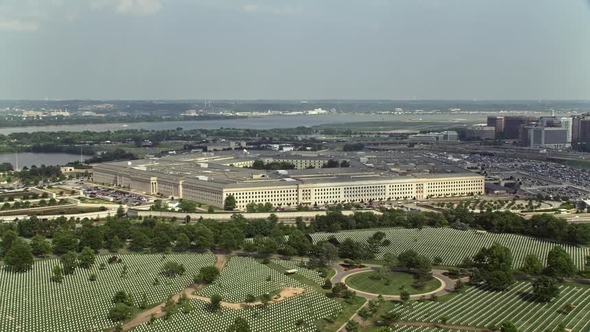 Aerial footage of Arlington National Cemetery with The Pentagon in the background on a partly cloudy day