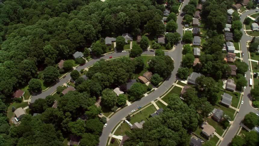 An aerial view of suburban neighborhoods in Fairfax Virginia during a sunny day with many single family homes and parked cars along the streets