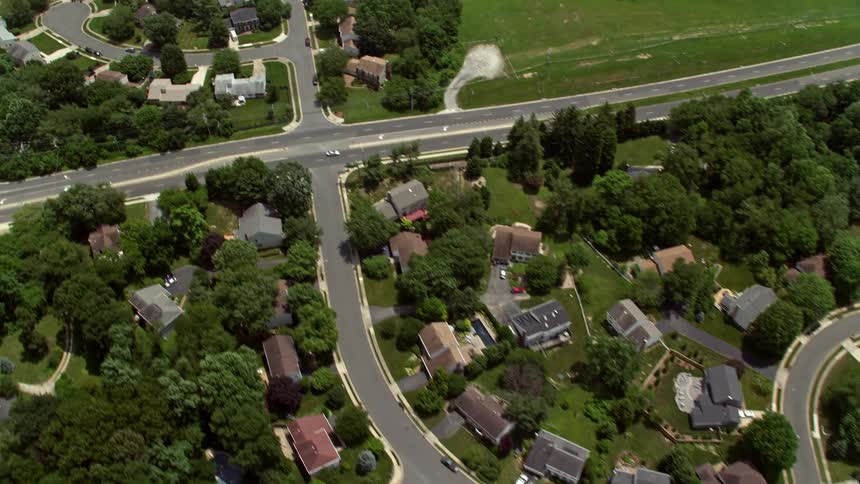 A sunny birds eye view of suburban neighborhoods in Fairfax VA with many streets and houses as cars travel on the roads and are parked on the roadside