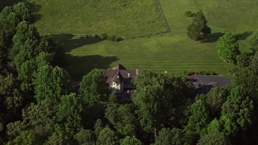 Aerial footage tracks an upscale home surrounded by lush green fields in Fairfax Station Virginia