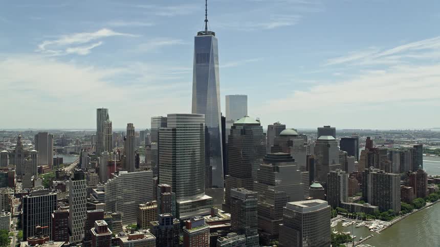 A beautiful aerial clip of Lower Manhattan featuring Freedom Tower and World Trade Center buildings captured during a partly cloudy day in New York Citys downtown area