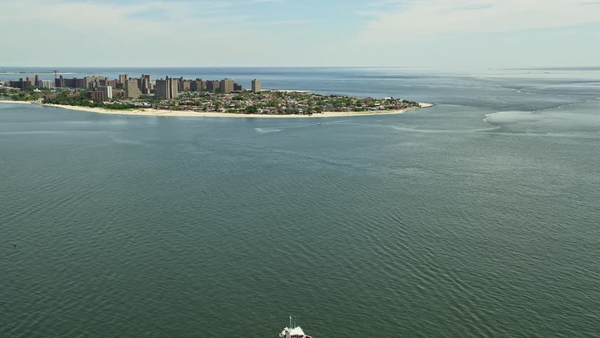 Approaching Coney Island by air this footage takes you over the sunny coastline of Brooklyn New York showcasing neighborhoods residences and seafaring activity
