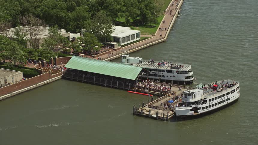 Tourists crowd the ferry dock on Liberty Island New York in aerial footage during the summer
