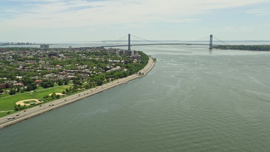 Approaching Verrazano-Narrows Bridge and Shore Parkway in NY Harbor aerial footage captures a sunny day on the suspension bridge
