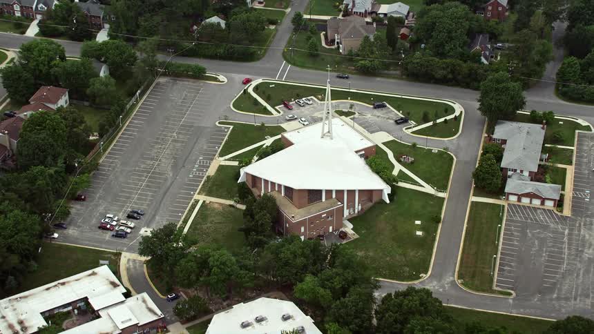 Aerial footage of Queen of the Apostles Catholic Church in Alexandria Virginia tilting down and approaching the church on a cloudy day