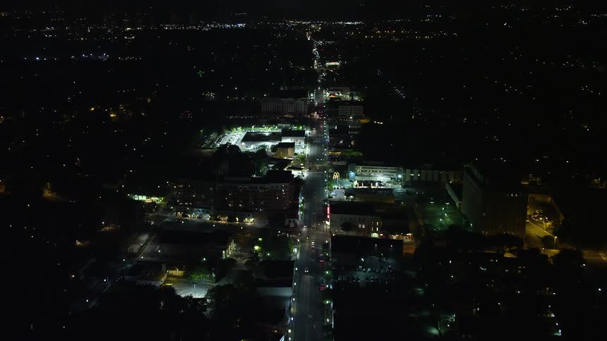 Flying over Columbia Pike at night approaching a car dealership and shops in suburban Arlington VA
