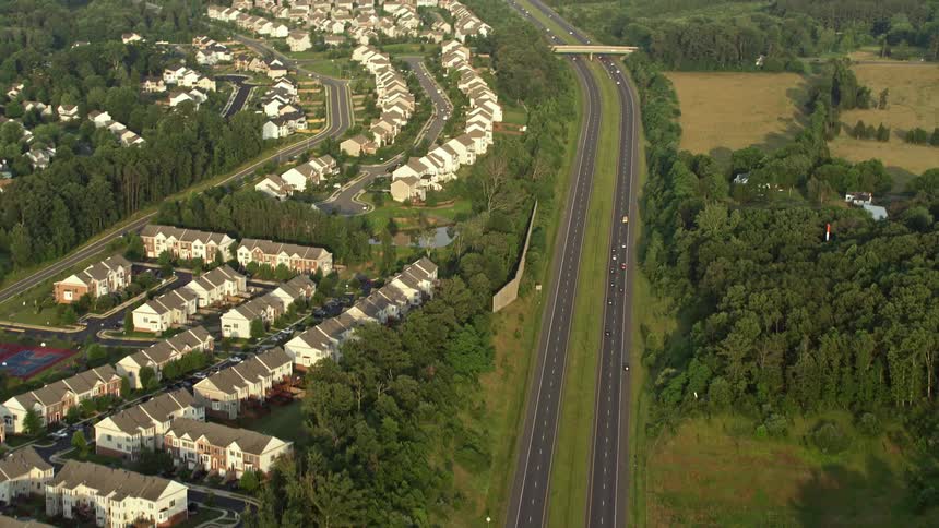 Aerial footage of vehicles driving through a suburban community on Prince William Parkway during sunset in Manassas Virginia