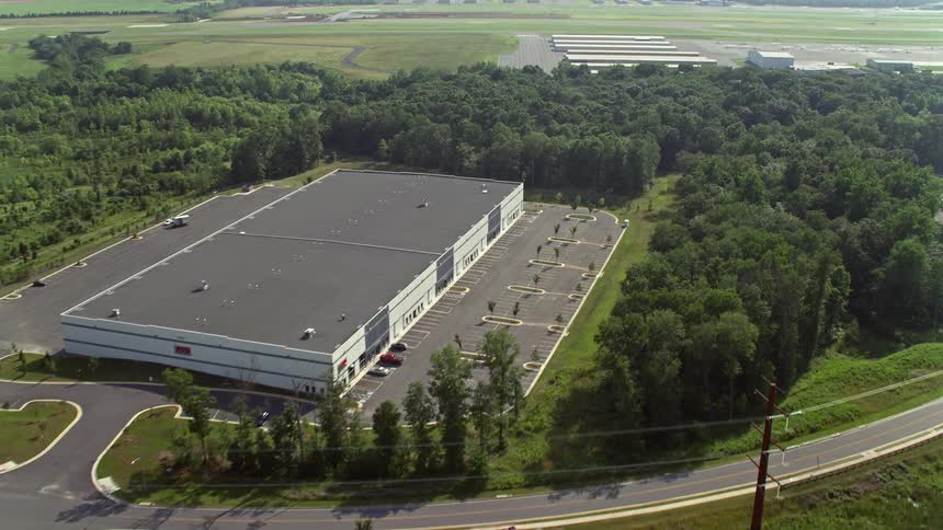 Approaching hangars at Manassas Regional Airport this aerial clip captures a birds eye view of warehouse buildings and nearby surroundings