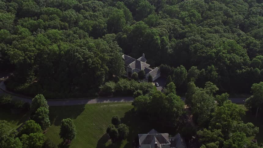 A sweeping aerial shot captures the beautiful birds eye view of a luxurious mansion amidst the hazy residential neighborhood in Fairfax Station Virginia