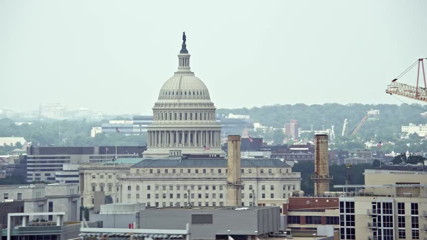 Aerial footage of the United States Capitol Dome with a construction crane in a hazy Washington DC