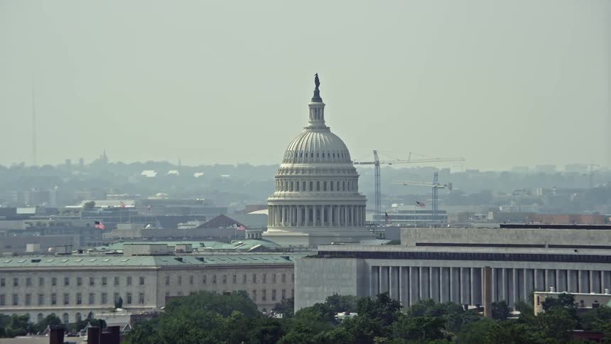 Flyby of the United States Capitol Dome viewed from the side including the Cannon House Offices and James Madison Building during a hazy summer day in Washington DC