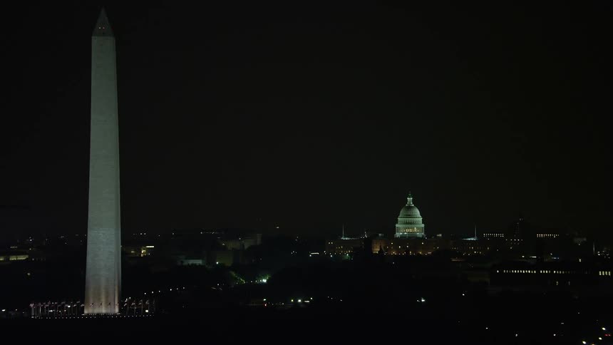 A breathtaking aerial footage of the historical United States Capitol Building and the iconic Washington Monument captured during a clear night in Washington DC