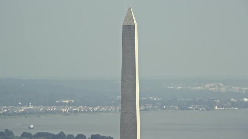 Aerial view of the White House and Washington Monument seen over rooftops of nearby office buildings during daytime