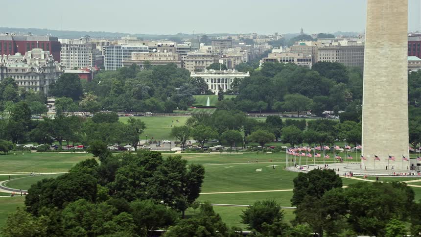 A stunning aerial footage of the iconic White House and Washington Monument in Washington DC showcasing the hustle and bustle of tourists visiting the landmark during daytime