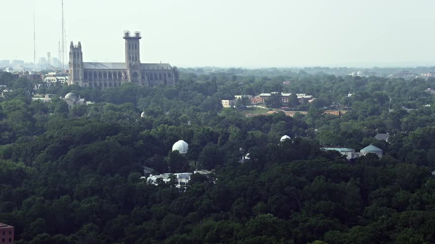 Aerial footage of Washington DC landmarks including the Washington National Cathedral Beauvoir Elementary School and the United States Naval Observatory on a hazy summer day