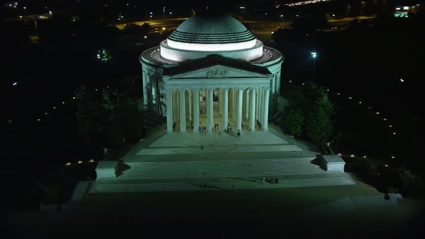 Aerial footage of the Jefferson Memorial in Washington DC at night with tourists visiting