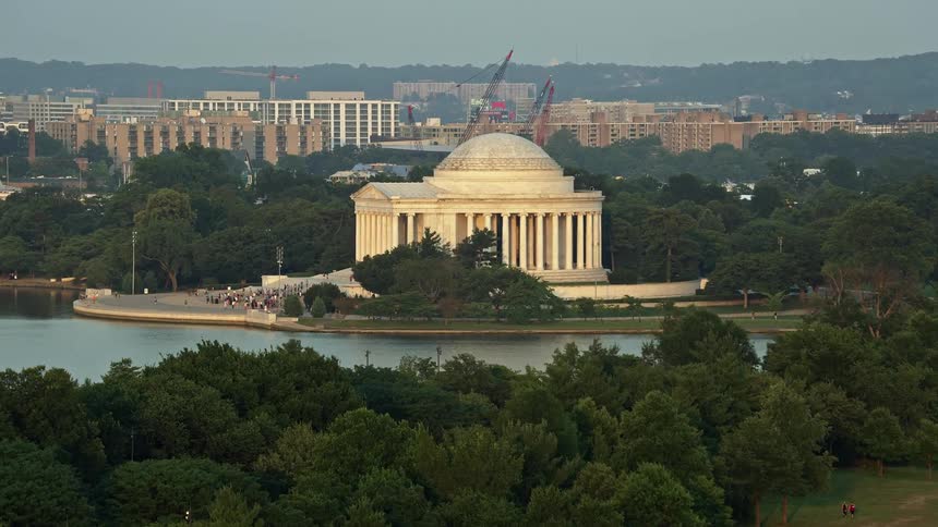 Approaching the iconic Jefferson Memorial at sunset with tourists in sight aerial footage captures the historical landmark in the haze of Washington DC
