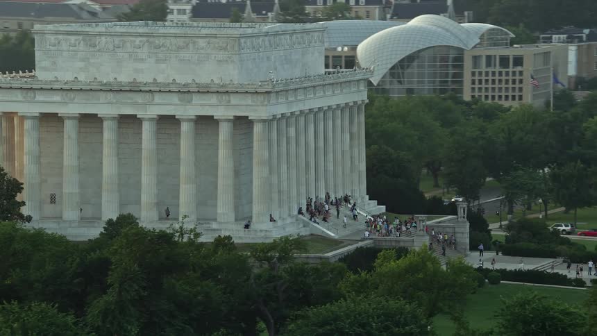 Aerial footage of Lincoln Memorial at sunset with tourists on the steps Washington DC
