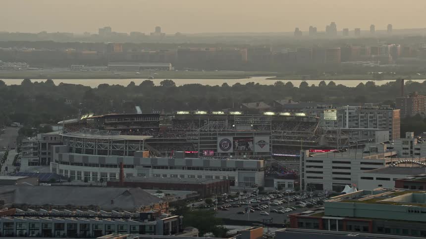 Aerial footage at sunset of packed Nationals Park baseball stadium with Ronald Reagan Airport visible in the background and Washington DC skyline