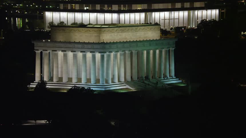 Aerial footage of visitors on the steps of the illuminated Lincoln Memorial at night in Washington DC