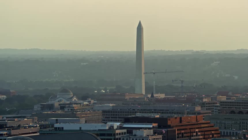 Aerial footage of iconic Washington Monument viewed at sunset from office buildings amidst hazy skies in Washington DC