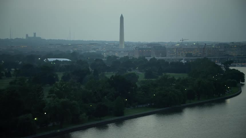 Aerial twilight footage captures the iconic structure of the Washington Monument in Washington DCs East Potomac Park surrounded by hazy greenery