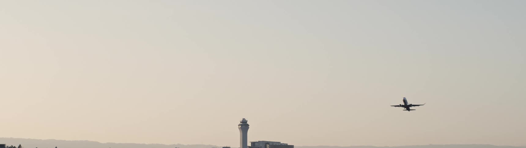 An airplane taking off from an airport flying across a clear sky
