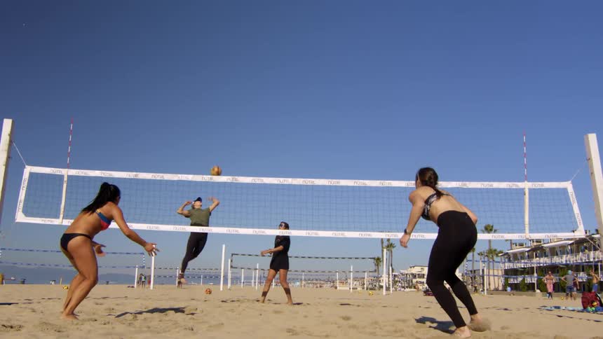 Four women playing volleyball on a beach court