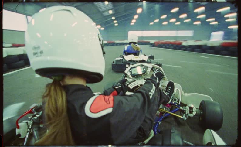 Two women in race cars racing on an indoor track