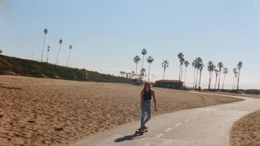 A woman is riding down a street on a skateboard