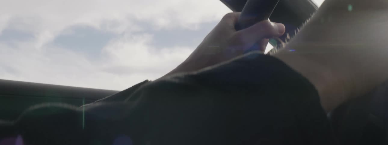 Close up of the hands of a man on the steering wheel of a car driving at daytime