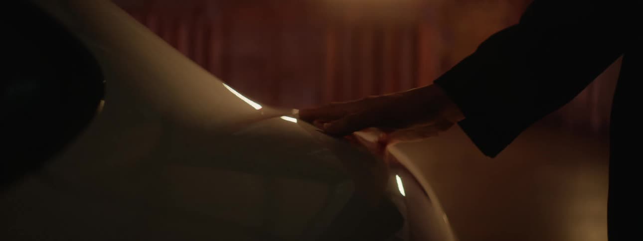 A white car being caressed by a persons hand