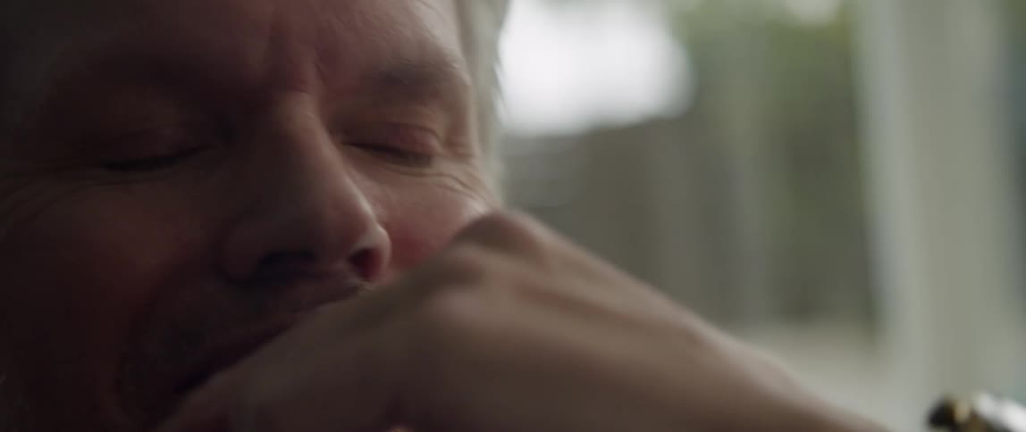 An up close of a man with his hand on his face looking into the distance contemplatively