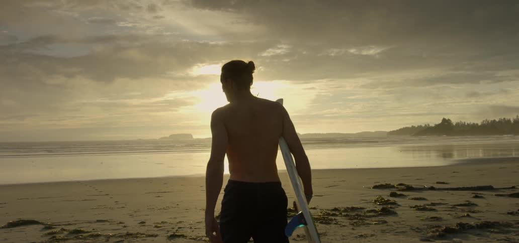 A man is walking towards the water with a surfboard