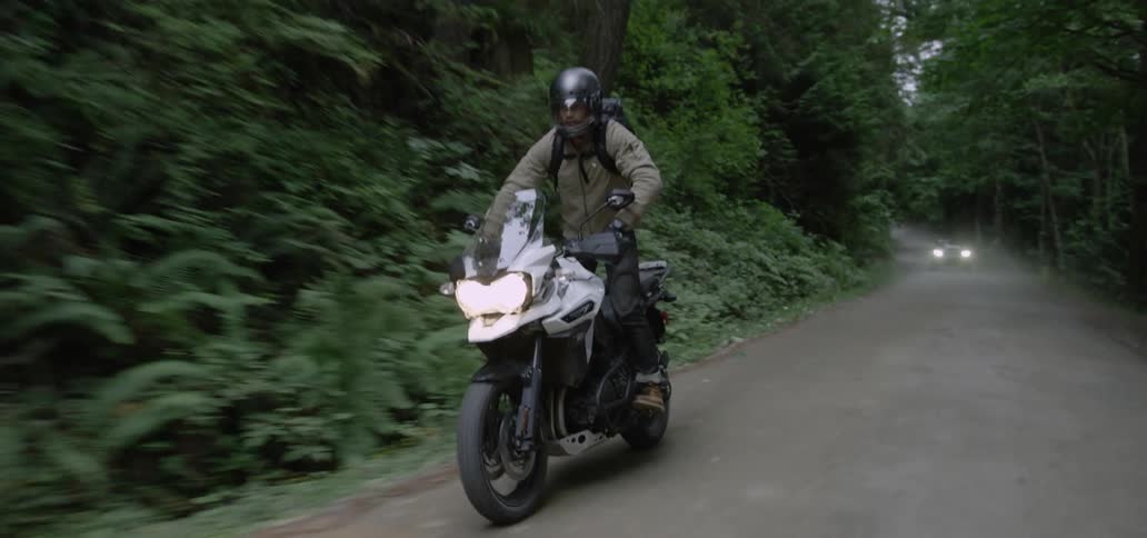 A motorcycle is riding down a small road