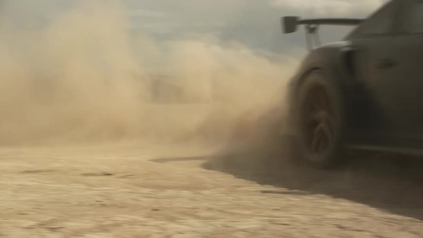 A driver drifts a sports car through the desert