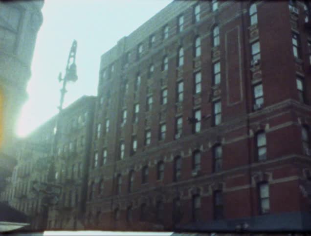 The side of a red brick building with many windows along a street