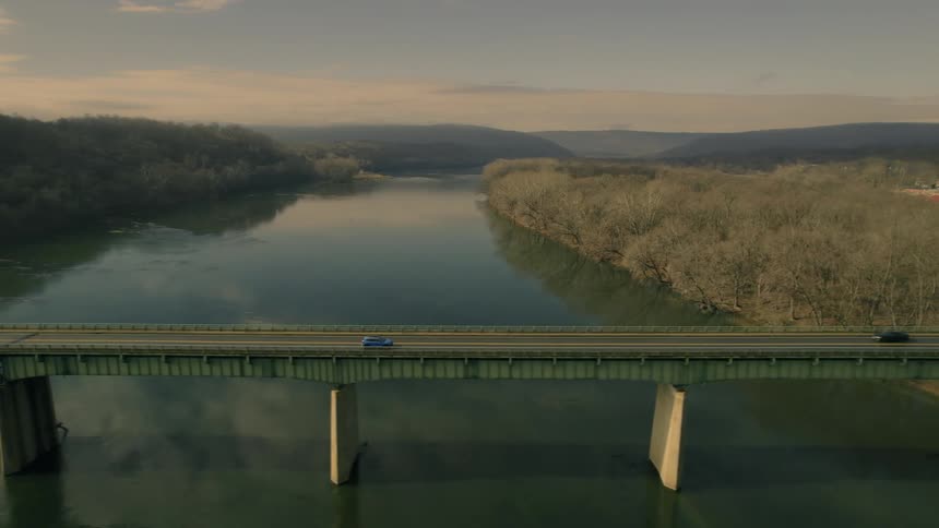 A car is driving on a bridge during sunset
