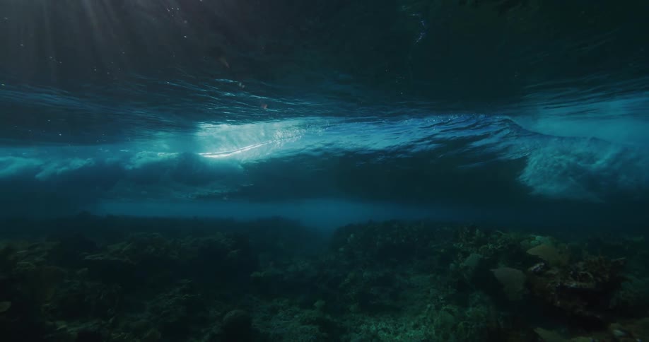 Waves moving forward while the camera surveys rocks underwater