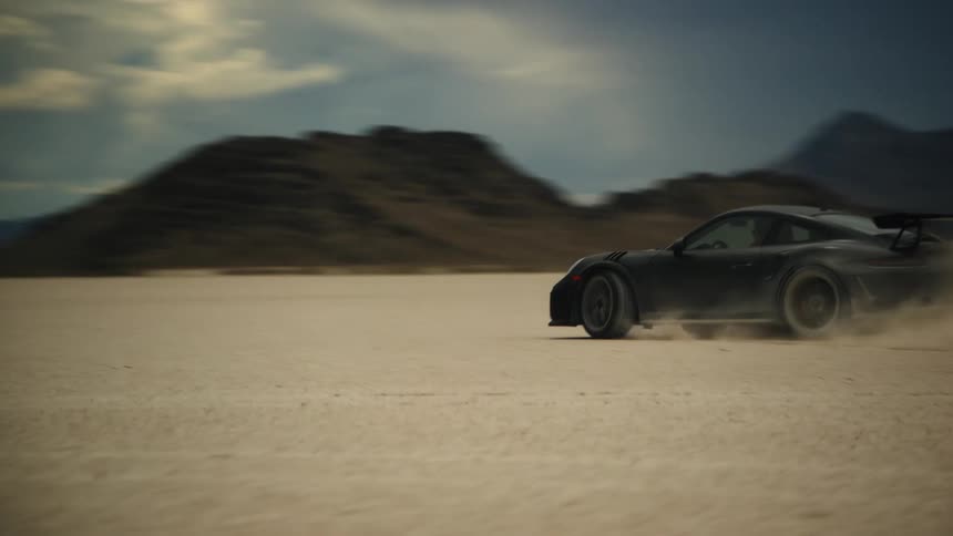 Dark gray sports car drifts to the left in the desert fast