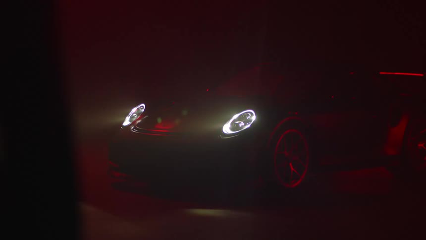 A woman is walking towards a car during the night time