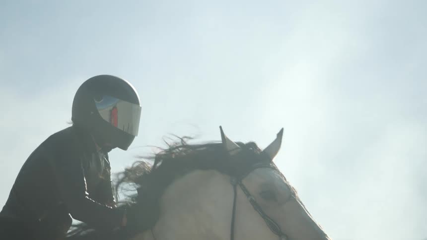A person wearing all black and a black helmet rides a horse