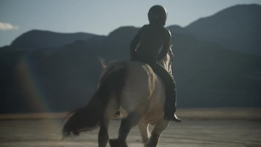 A person is horse back riding outdoors at dusk