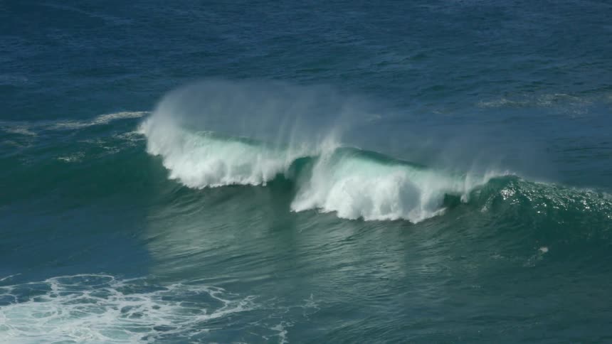 Aerial view of ocean wave breaking against the shore