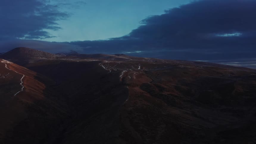 Dark blue gray clouds sit over hills and mountains