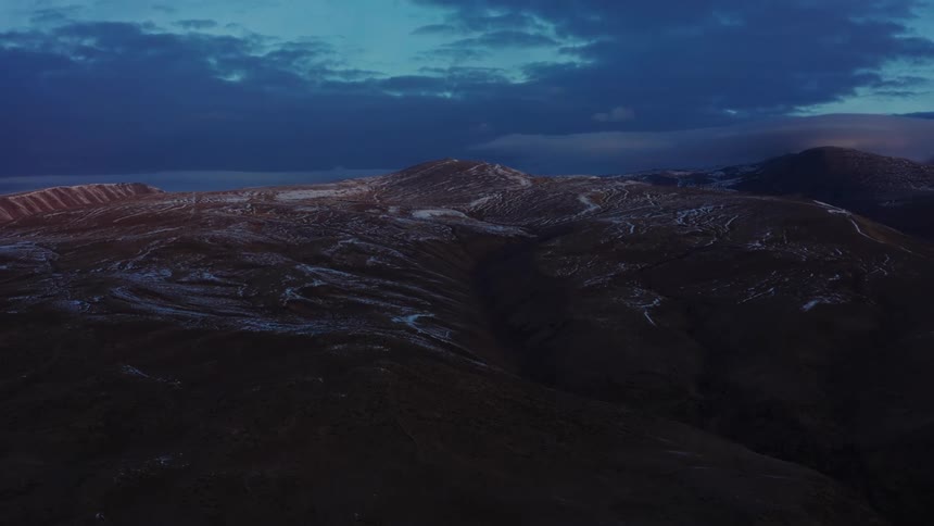 The top of a mountain range against a blue cloudy sky